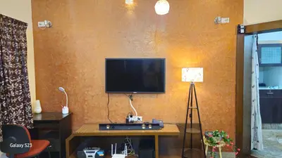 a living room with a television on a wall at JEO Home Stay And Hospitality in Mysore