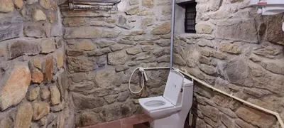 a stone bathroom with a toilet and a stone wall at bandipur stay in Tāmarakarai