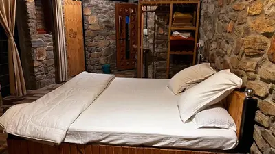 a bed in a room with a stone wall at bandipur stay in Tāmarakarai