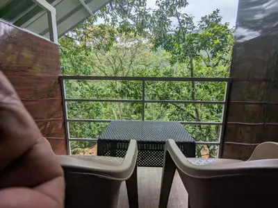 a table and chairs on a balcony with a view of trees at Ashokavanam Heritage Village by N Square in Kanthalloor
