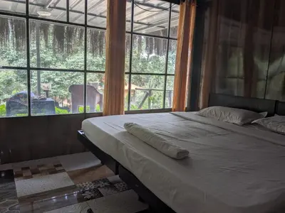 a bed in a room with a large window at Ashokavanam Heritage Village by N Square in Kanthalloor