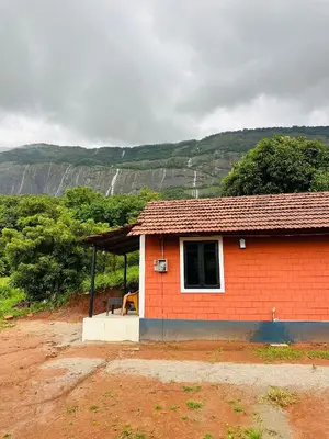 a small red brick house with a bench in front at Jungle Homes in Kollengode
