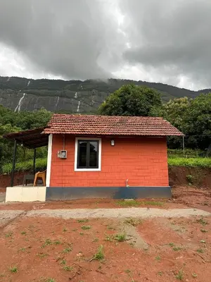 a small red brick house with a window at Jungle Homes in Kollengode