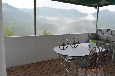 a table and chairs on a balcony with a mountain view at Jungle View Homestay Anakulam in Viripara