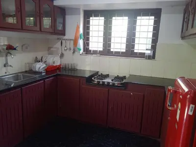 a kitchen with red cabinets and a stove in it at Ocean blue home stay in Pallipuram