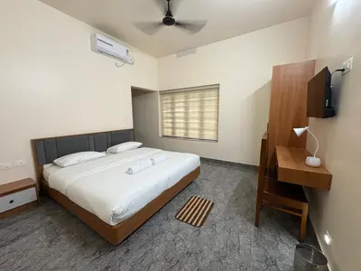 a bedroom with a large bed and a television at Keshavam Homestay in Guruvāyūr