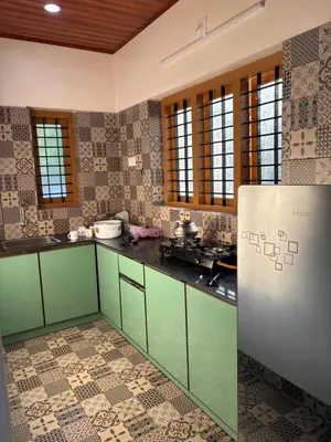 a kitchen with green cabinets and a refrigerator at Keshavam Homestay in Guruvāyūr
