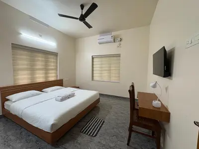 a bedroom with a bed and a desk and a television at Keshavam Homestay in Guruvāyūr