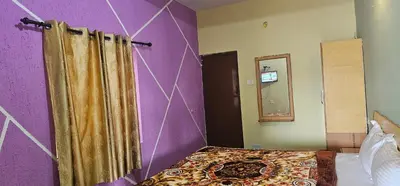 a bedroom with a purple wall with a bed and a mirror at Stay Awhile Cottages in Ooty