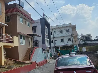 a red car parked in a street next to buildings at Stay Awhile Cottages in Ooty