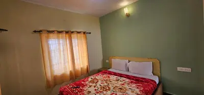a bedroom with a bed with a red comforter and a window at Stay Awhile Cottages in Ooty