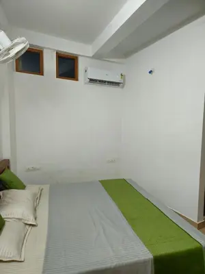 a bedroom with a large bed with a green blanket at RF Tower in Kozhikode
