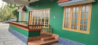 a green house with a staircase and windows at Wayanad views in Vythiri