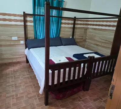 a bedroom with a wooden bed with a canopy at Wayanad views in Vythiri