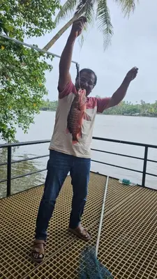 a man standing on a boat with his arms in the air at Rivulet Dale in North Paravur