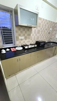 a kitchen with a counter with a stove and a window at Brindavan Service Apartments in Mysore