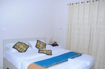 a white bed with pillows on top of it at Brindavan Service Apartments in Mysore