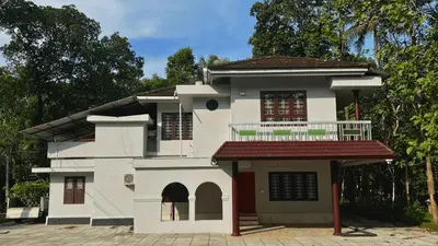 a white house with a balcony on top of it at Pepper Nut Homestay in Thattakād