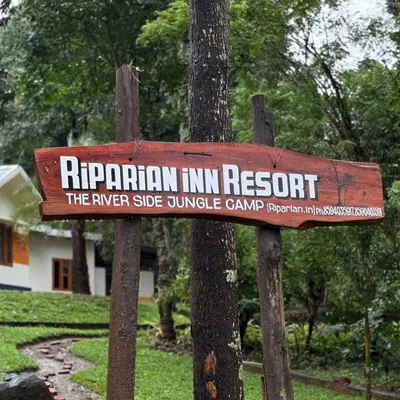 a sign for a ripponian inn resort on a tree at Riparian Inn Resort in Chekadi