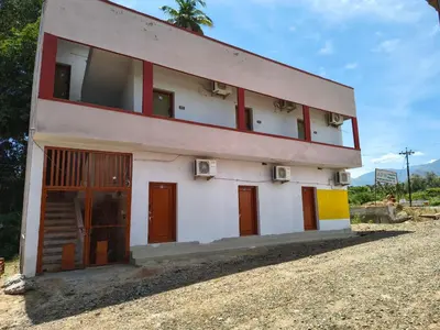 a building with red doors on the side of it at APM Lodge in Palaiya Ayakkudi