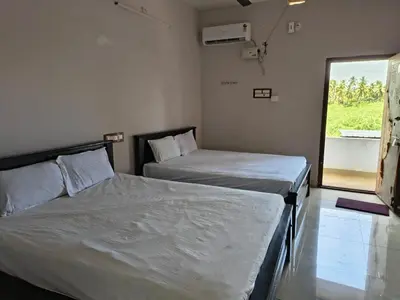 two beds in a room with a window at APM Lodge in Palaiya Ayakkudi