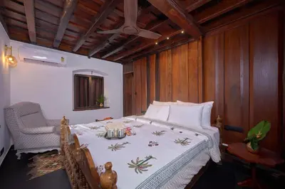 a bedroom with a bed with a table and a chair at Seclude Karthika Nivas, Thrissur in Trichūr