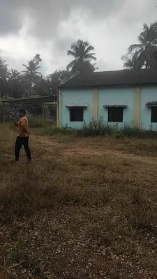 a man walking in a field next to a building at NKM Holiday Park in Shrīrangapattana