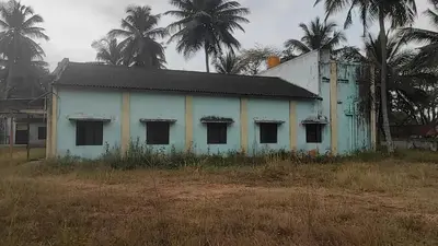 an old white house with palm trees in the background at NKM Holiday Park in Shrīrangapattana