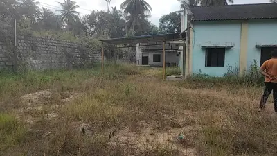 a man standing in a field next to a house at NKM Holiday Park in Shrīrangapattana
