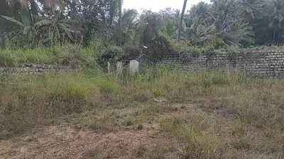 a stone wall in a field next to a fence at NKM Holiday Park in Shrīrangapattana