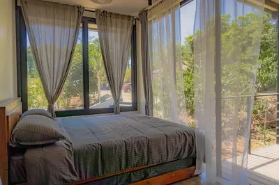 a bedroom with a bed in front of large windows at Trumpet Deck 3BHK Container Home in Kutta