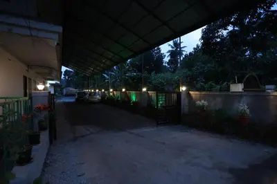 a building with a gate and a fence with lights at Emberlin Holidays in Wayanad