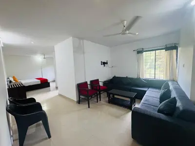 a living room with a couch and chairs and a bed at Moon Way in Neriyamangalam