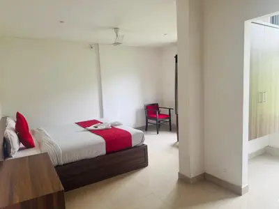 a bedroom with a bed and a red chair at Moon Way in Neriyamangalam