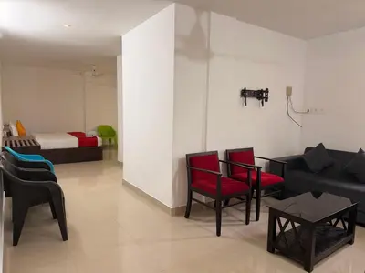 a living room with a couch and chairs and a bed at Moon Way in Neriyamangalam