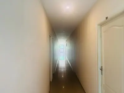 a long hallway with a white wall and a ceiling at Moon Way in Neriyamangalam