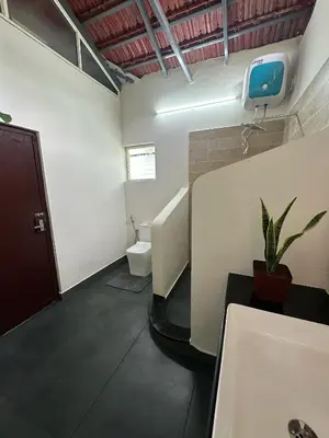 a bathroom with a toilet and a tv on the wall at Sky Holiday Homestay Cottages Madikeri Kushalnagar Coorg in Kushālnagar