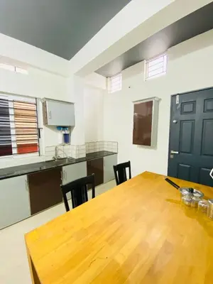 a room with a wooden table and a kitchen at Verito Home Stay