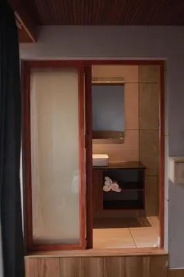 a bathroom with a glass door with a mirror at Mercure Resort Wayanad in Mananthavady