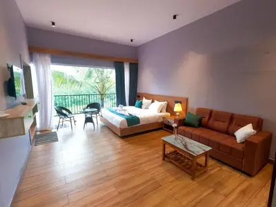 a living room with a couch and a bed and a table at Mercure Resort Wayanad in Mananthavady