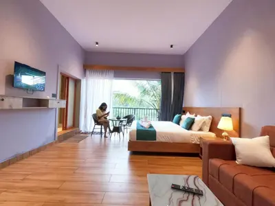 a hotel room with a bed and a woman sitting at a table at Mercure Resort Wayanad in Mananthavady