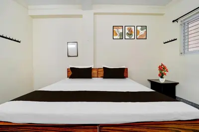 a bedroom with a large white bed with black pillows at Super Collection O Avarampalayam Bus Stop Formerly Krish Castle in Coimbatore