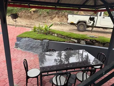 a table and chairs on a patio with a truck at Misty huts home stay in Madikeri