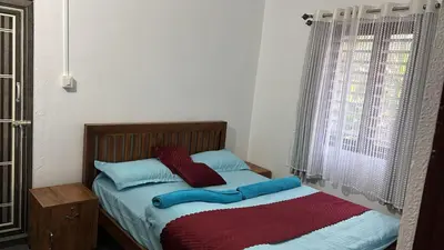 a bed with red and blue pillows and a window at Misty huts home stay in Madikeri