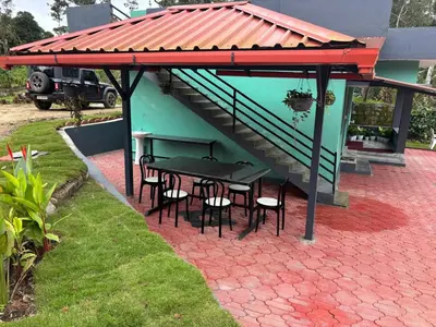 a patio with a table and chairs under a roof at Misty huts home stay in Madikeri