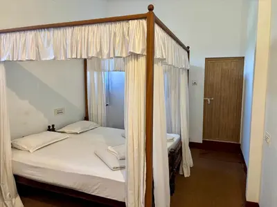 a bedroom with a canopy bed with white sheets at FAMILY RESORT MARAYOoR KANTHALLOOR in Kanthalloor
