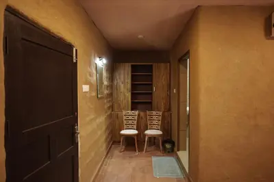 a hallway with two chairs and an open door at Papilio Mudhouse Stay in Edayūr