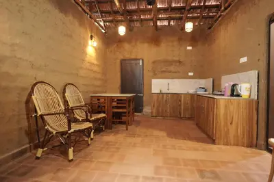 a kitchen with two chairs and a table in a room at Papilio Mudhouse Stay in Edayūr