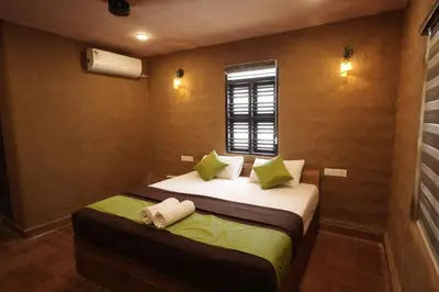 a bedroom with a bed with green pillows and a window at Papilio Mudhouse Stay in Edayūr