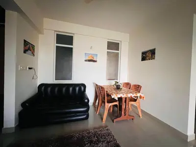 a living room with a table and a black leather couch at Pearl Home Luxury 3Bhk family-friendly Appartment in Mysore